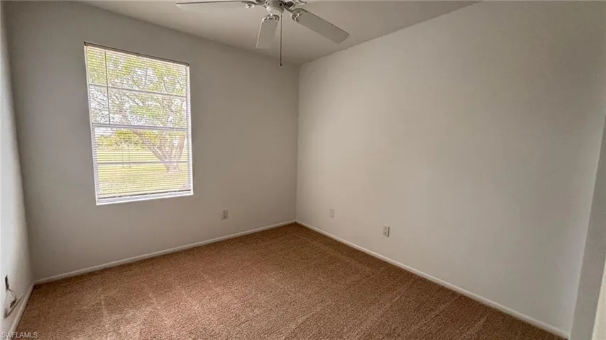 Carpeted empty room featuring baseboards and ceiling fan