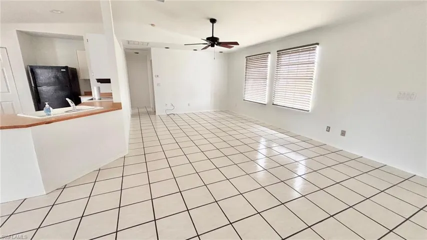 Unfurnished living room with light tile patterned floors and ceiling fan