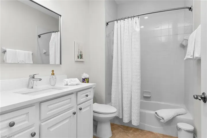 Bathroom with tub and shower combination, single vanity with updated cabinetry, new white quartz countertops, tile flooring, and recessed lighting.
