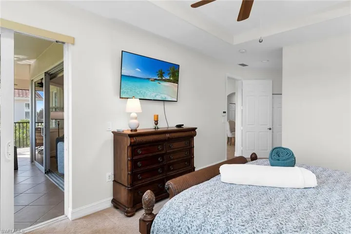 Spacious primary bedroom featuring vaulted ceilings, neutral finishes, and sliding glass doors opening to the lanai.
