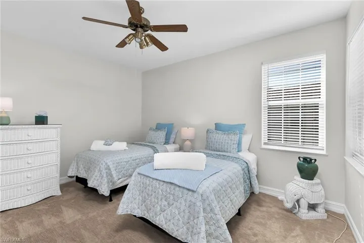 Second bedroom with light colored carpet and a ceiling fan.