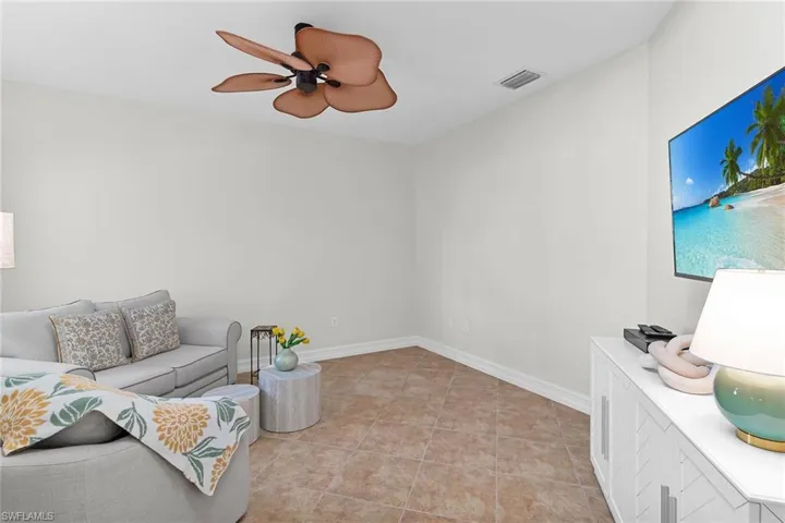 Den featuring tile flooring, a ceiling fan, and multiple windows.