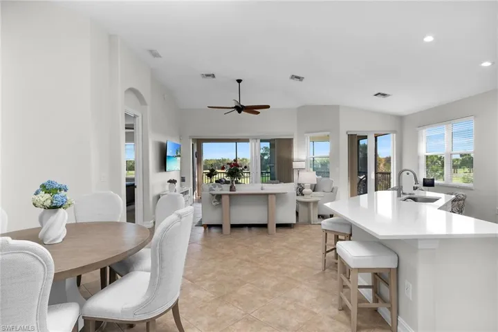 Open-concept living and kitchen area featuring vaulted ceilings, recessed lighting, quartz countertops, stainless steel appliances, and an oversized island with breakfast bar, all designed to highlight the bright interior and expansive views beyond.