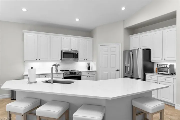 Bright, fully updated kitchen featuring brand-new quartz countertops, updated cabinetry, stainless steel appliances, recessed lighting, vaulted ceilings, and a spacious island.