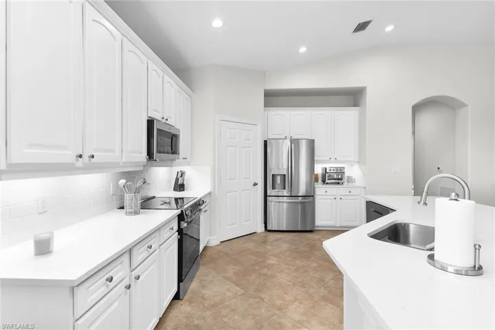 Bright, fully updated kitchen featuring brand-new quartz countertops, updated cabinetry, stainless steel appliances, recessed lighting, vaulted ceilings, and a spacious island.