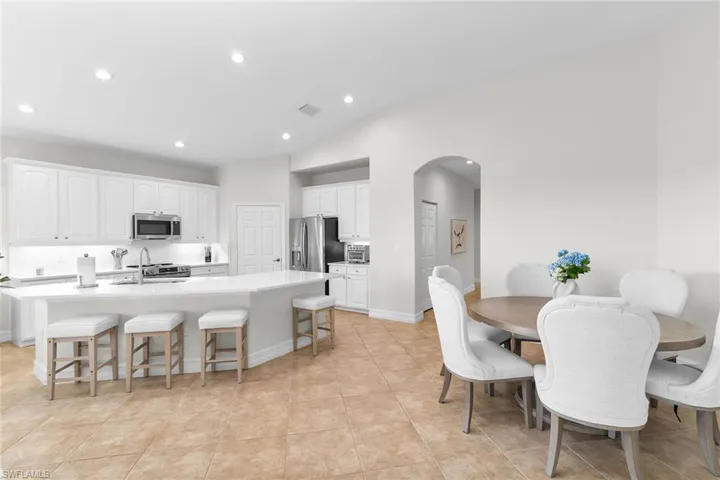 Spacious great room featuring vaulted ceilings, recessed lighting, and an effortless transition from the dining area to the beautifully renovated kitchen.