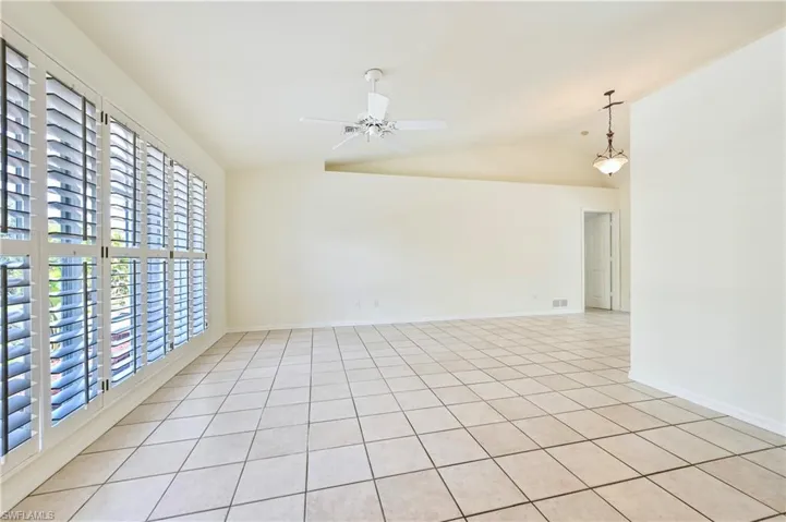 Unfurnished room with ceiling fan, light tile patterned floors, and vaulted ceiling
