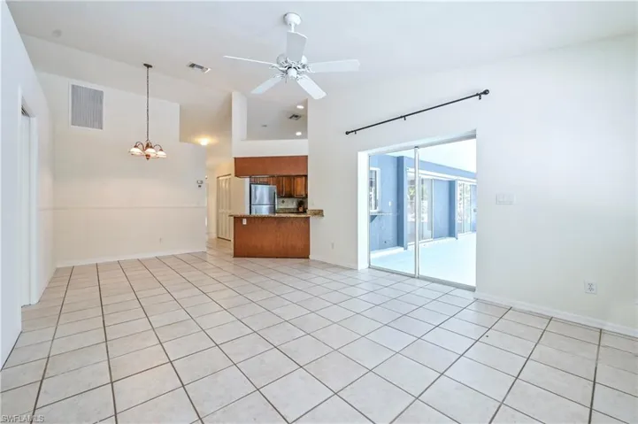 Unfurnished living room featuring light tile patterned flooring and ceiling fan with notable chandelier