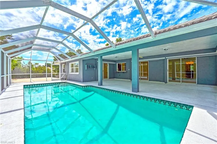 View of swimming pool with a patio area, a lanai, and a wall unit AC