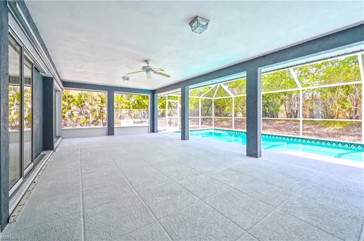 View of pool with a lanai, a patio area, and ceiling fan