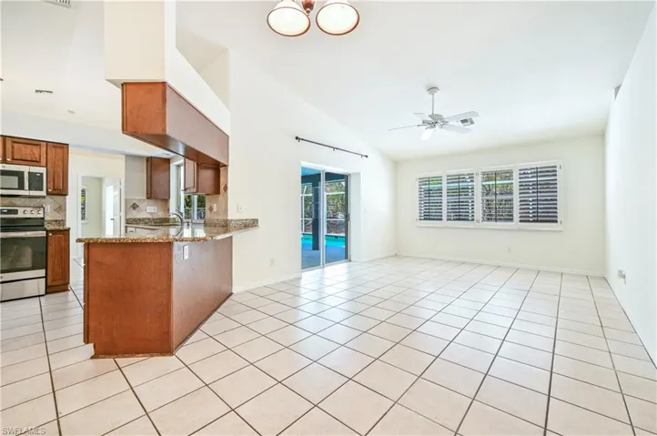 Kitchen with light stone countertops, ceiling fan, stainless steel range oven, kitchen peninsula, and light tile patterned floors