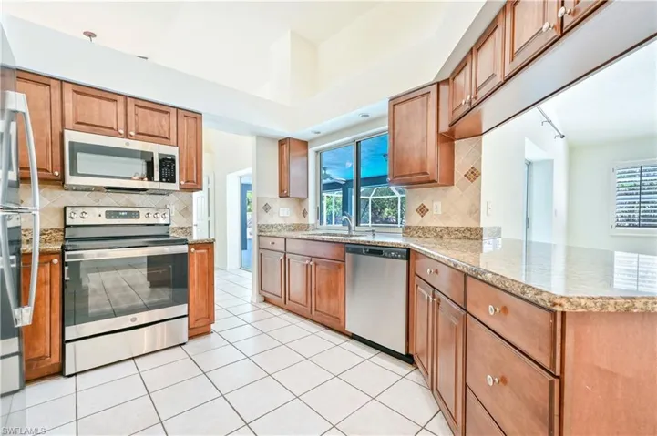Kitchen featuring sink, stainless steel appliances, backsplash, kitchen peninsula, and light tile patterned floors
