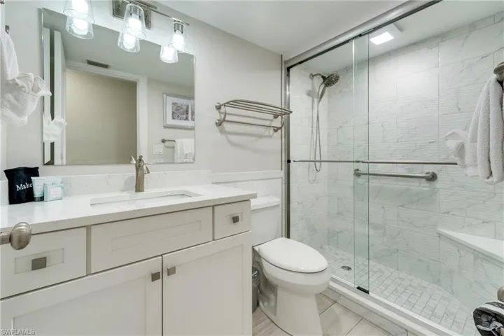 Bathroom with vanity, a stall shower, and a wainscoted wall