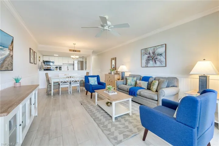 Living room featuring a wainscoted wall, ornamental molding, and ceiling fan