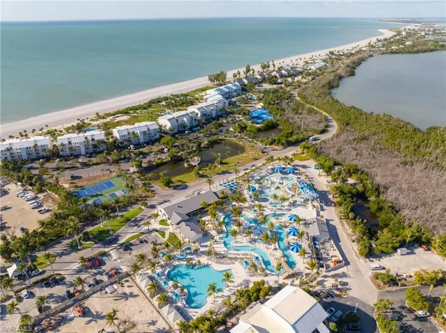 Aerial view of property and surrounding area featuring expansive coastline and a pool area