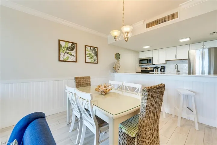 Dining room featuring a wainscoted wall, crown molding, a chandelier, and wood finish floors