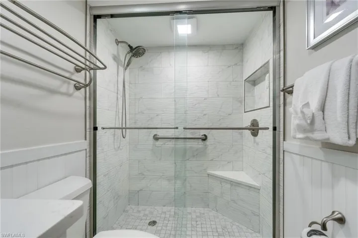Full bath featuring a wainscoted wall, a stall shower, and a decorative wall