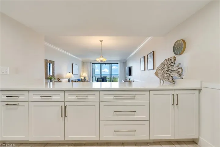 Kitchen featuring white cabinets, open floor plan, pendant lighting, light stone counters, and a peninsula