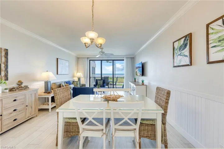 Dining space featuring a wainscoted wall, crown molding, light wood-type flooring, and a ceiling fan