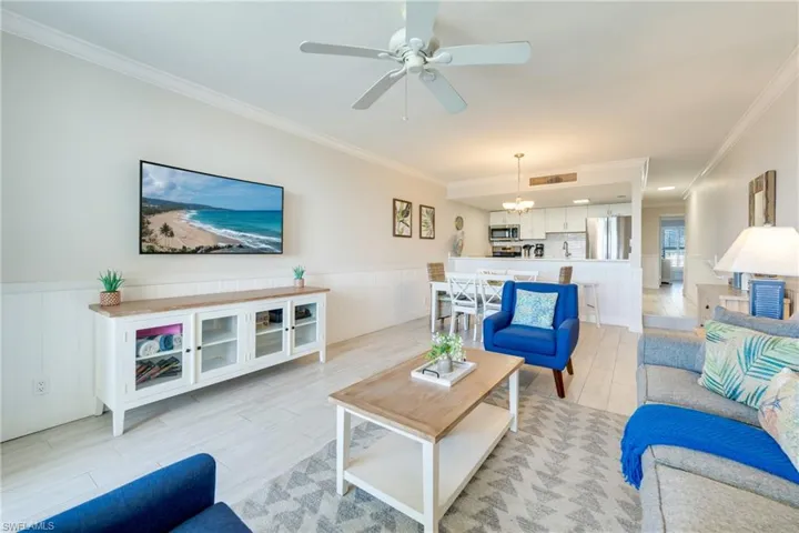 Living area featuring crown molding, a wainscoted wall, ceiling fan, and a chandelier