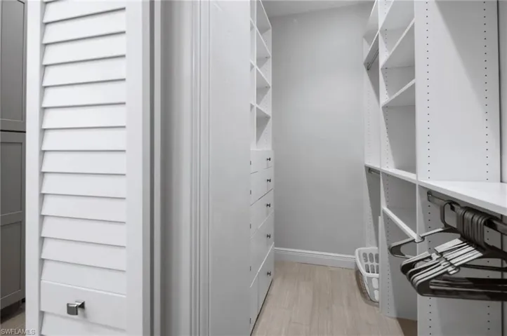 Custom closet system featuring white shelving, built-in drawers with modern hardware, and wood-finish flooring