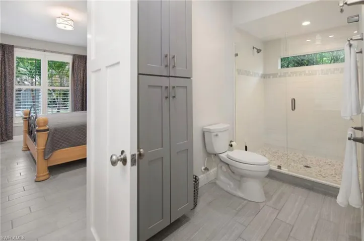 Spacious bathroom featuring a glass-enclosed shower with pebble flooring and a tiled accent band