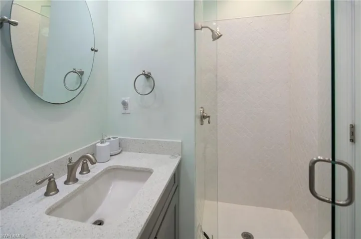 Bathroom featuring a walk-in shower with glass enclosure, white textured tile, and brushed nickel fixtures