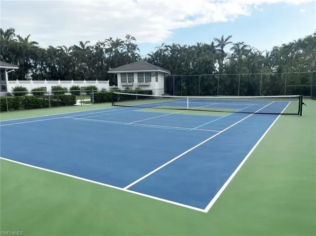 Regulation-size tennis court featuring a blue playing surface with white lines and green surrounds
