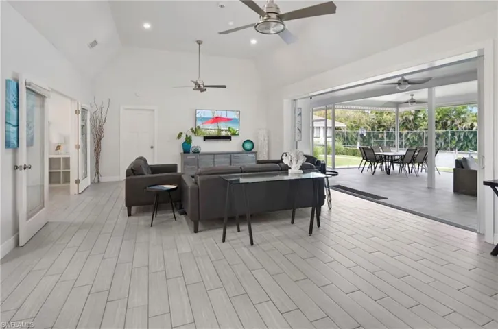 Spacious living area featuring light wood-finish flooring, vaulted ceilings, and recessed lighting