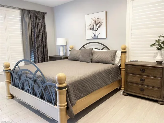 Bedroom featuring wood-finish flooring, plantation shutters, and a wall-mounted art piece