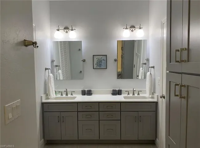 Dual vanity featuring shaker-style cabinetry, quartz countertops, and brushed nickel fixtures
