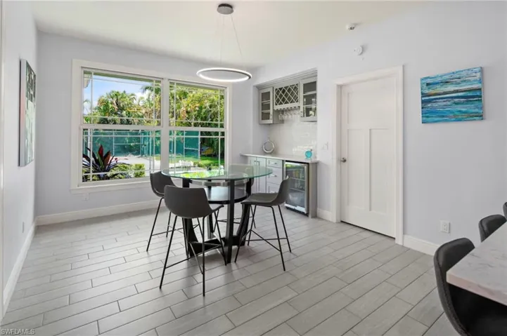 Dining area featuring a built-in wet bar with cabinetry, a beverage refrigerator, and a tile backsplash