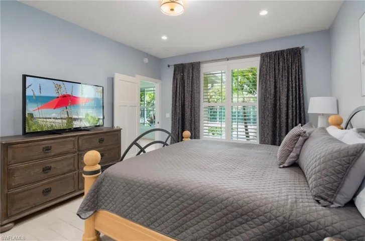 Room featuring light blue walls, recessed lighting, white window shutters, and a sliding door with frosted glass panels