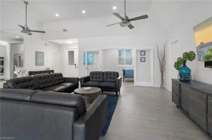 Spacious living area featuring vaulted ceilings, recessed lighting, and two ceiling fans