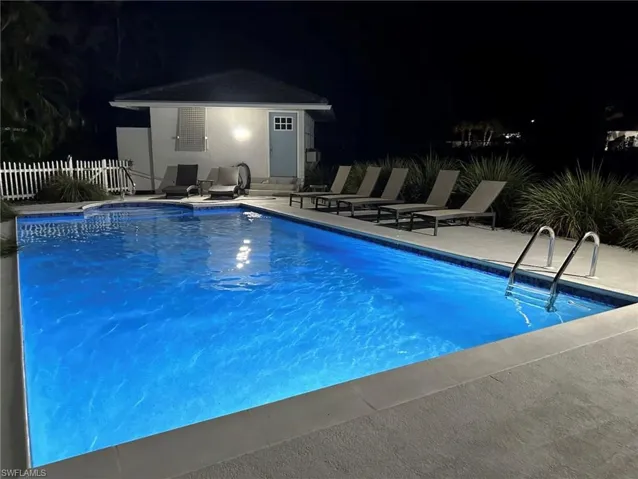 Illuminated swimming pool with integrated spa and surrounding concrete decking