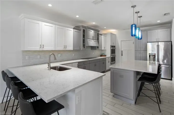Contemporary kitchen featuring two-tone cabinetry, stainless steel appliances, and light-toned countertops