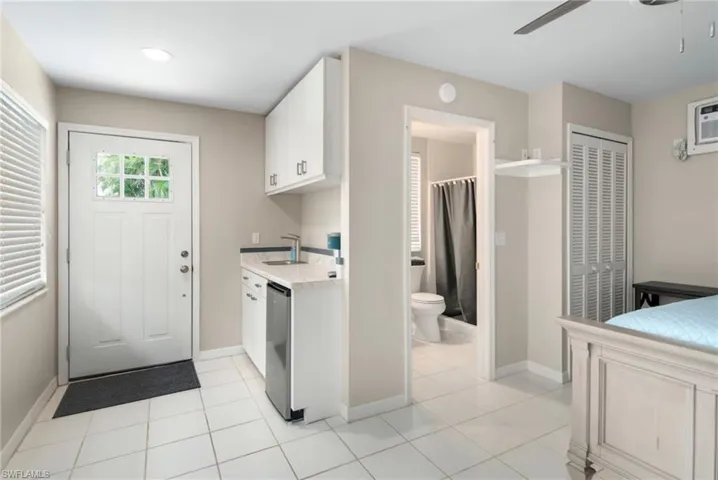 Compact kitchenette featuring white cabinetry, a sink, and an undercounter refrigerator