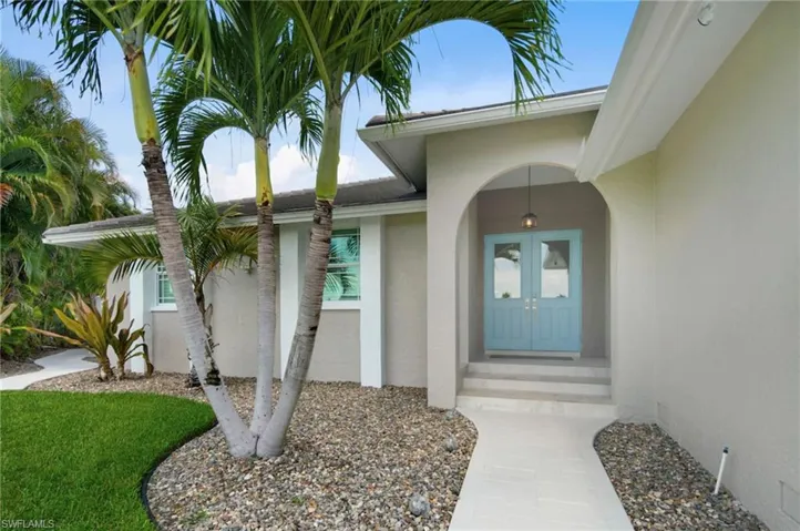 Welcoming arched entry with a light blue double door and transom windows