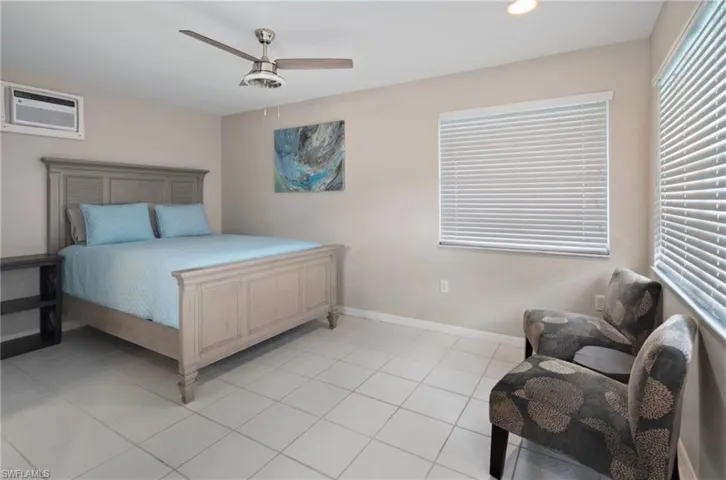 Spacious room featuring light-colored square tile flooring, neutral wall paint, and a built-in window air conditioning unit