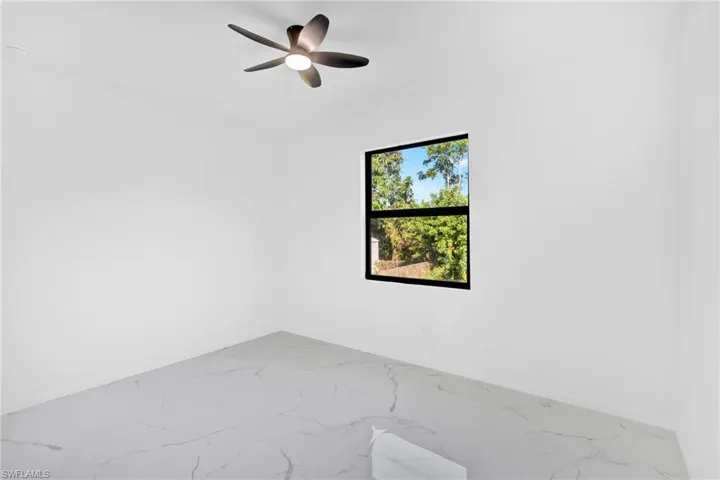 Unfurnished room featuring marble look tiles and ceiling fan