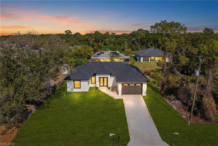 View of front of home with a yard, concrete driveway, stucco siding, and a garage