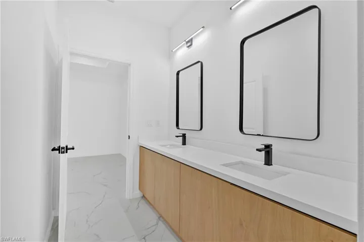 Bathroom with double vanity and light marble finish flooring