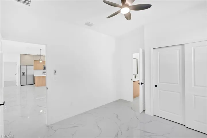Unfurnished bedroom with stainless steel built in fridge, light marble finish flooring, a closet, and ceiling fan