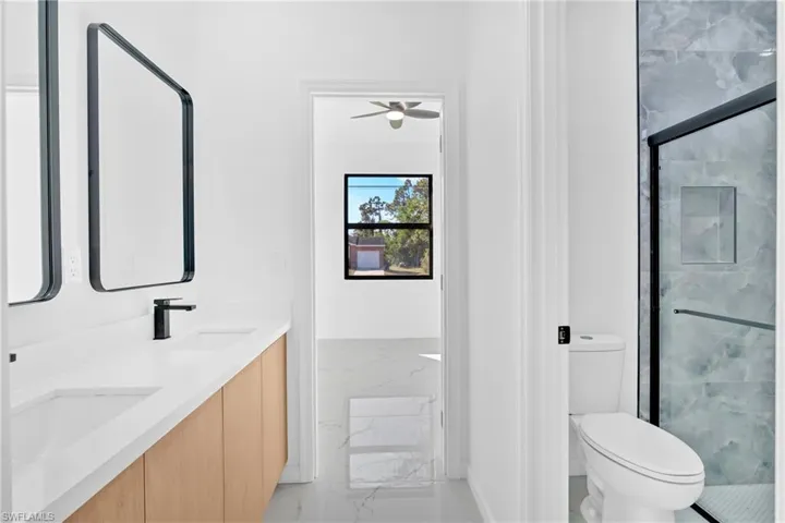 Full bathroom with a marble finish shower, double vanity, ceiling fan, and light marble finish floors