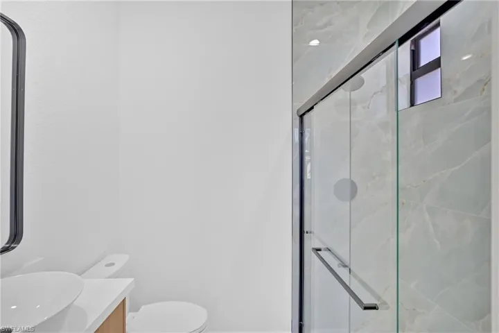 Bathroom with vanity and a marble finish shower
