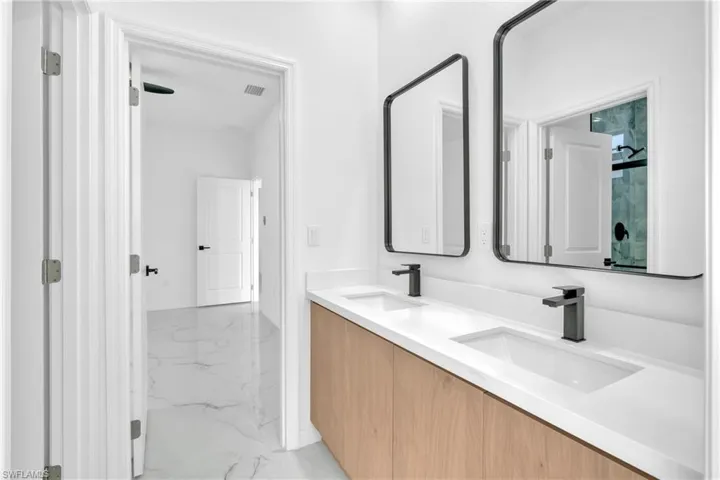 Full bath with double vanity and light marble finish floors