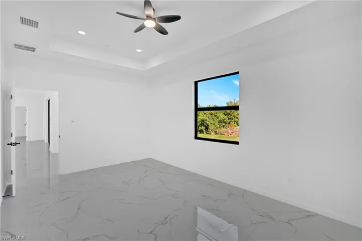 Unfurnished room featuring recessed lighting, marble finish flooring, a tray ceiling, and a ceiling fan