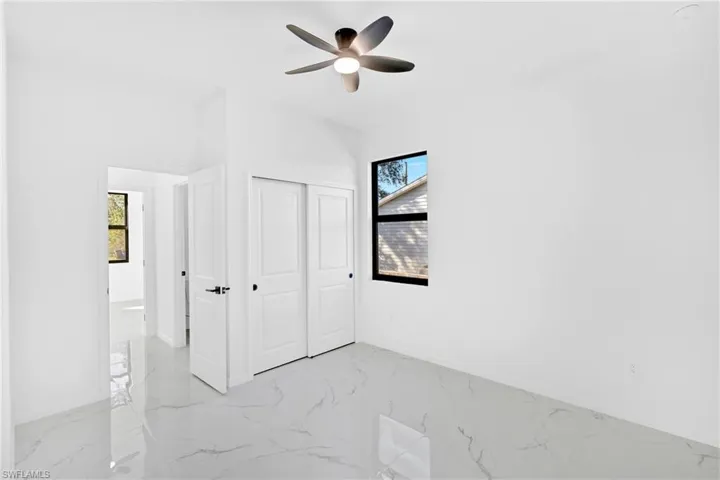 Unfurnished bedroom featuring light marble finish flooring, a closet, and ceiling fan
