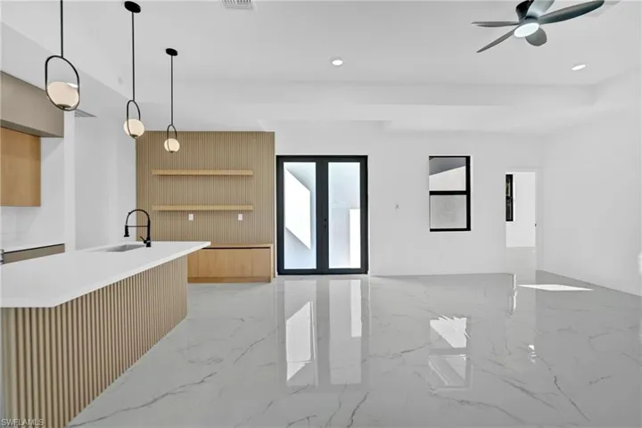 Kitchen featuring hanging light fixtures, light marble finish floors, french doors, open shelves, and light stone counters