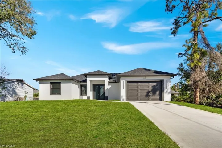 Prairie-style home with a front lawn, stucco siding, concrete driveway, a garage, and a shingled roof